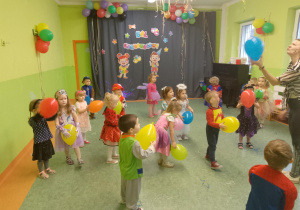 Sala gimnastyczna. Dzieci w przebraniach tańczą podczas balu karnawałowego. W tle dekoracja tematyczna.