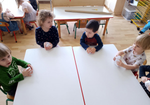 Sala przedszkolna. Dzieci siedzą przy stoliku i wykonują pracę plastyczną ,,Amore pomidore"