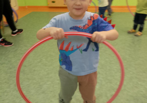 Sala gimnastyczna. Chłopiec prezentuje koło hula-hop.