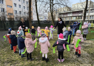Ogród przedszkolny. Dzieci tańczą z szarfami z zielonej bibuły.