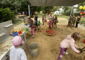 Dzieci podczas zabaw sensorycznych w ogrodzie przedszkolnym.