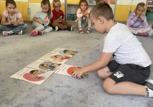 Dzieci na dywanie omawiają karty z "Kodeksem Przedszkolaka".