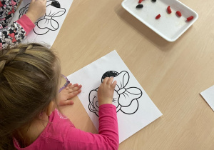 dziewczynka w różowej bluzce wykleja plasteliną myszkę miki