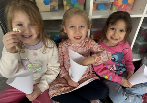 dzieci w sali przedszkolnej jedzą popcorn z papierowych rożków