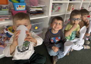 dzieci w sali przedszkolnej jedzą popcorn z papierowych rożków