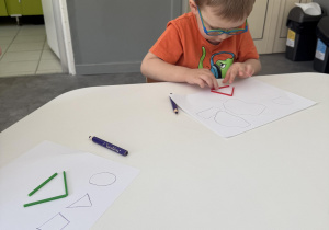 chłopiec układa figury geometryczne z kolorowych patyczków