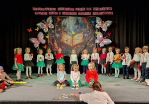 Dzieci stojąc na scenie graja na instrumentach muzycznych