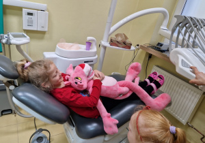 dziewczynka z maskotką leży na fotelu dentystycznym