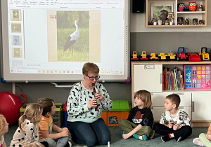 Nauczycielka prezentuje dzieciom głos kukułki grając na flecie