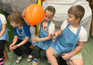 Dziewczynka trzyma butelkę z suchym lodem, dzięki któremu napompowuje się umieszczony na butelce balon