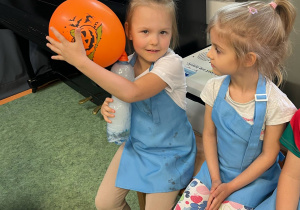 Dziewczynka trzyma butelkę z suchym lodem, dzięki któremu napompowuje się umieszczony na butelce balon
