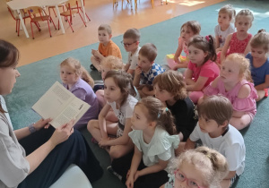 Dzieci słuchają książki czytanej przez mamę jednej z dziewczynek