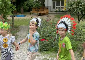 Dzieci podczas zabaw w ogrodzie przedszkolnym z indiańskimi pióropuszami na głowie