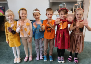 Dzieci pozują do zdjęcia w jesiennych strojach