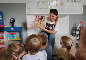 Pani pokazuje dzieciom ilustrację w książce "Tata Oli i piłkarska gorączka"