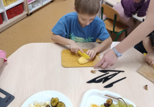 Chłopiec kroi gruszkę