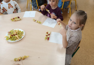 Dzieci zajadają się samodzielnie przygotowanymi szaszłykami owocowymi