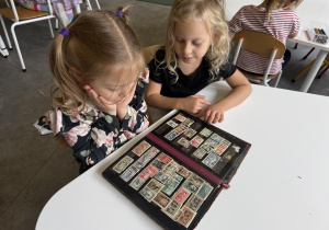 dzieci oglądają klaser ze znaczkami pocztowymi