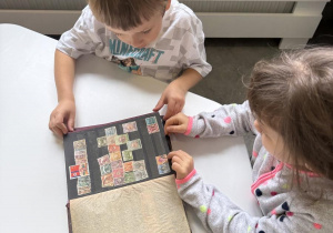 dzieci oglądają klaser ze znaczkami pocztowymi