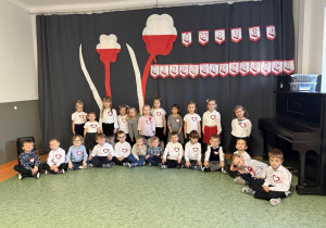 dzieci w eleganckich strojach z kotylionami pozują na Święto Niepodległości