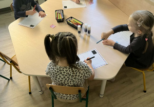 Dzieci ozdabiają i kolorują przy stoliku swoje pocztówki