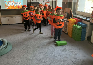 Dzieci podczas zajęć ruchowych w grupie na dywanie w strojach dyni
