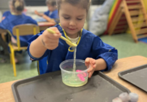 Dziewczynka mieszająca w pudełku plastikowym składni do wykonania slime