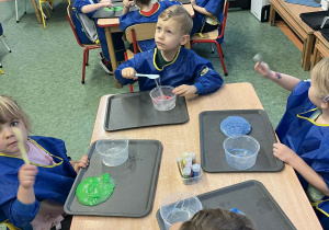 Dzieci przy stolikach wykonujący slime podczas warsztatów
