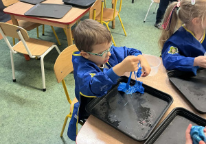 Dzieci przy stolikach wykonujący slime podczas warsztatów