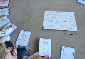 Dzieci siedzą w kole z narysowanymi wspólnie przedszkolnymi potworami