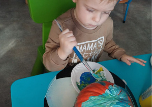 dziecko maluje dynię