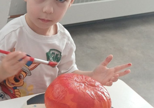 dziecko ozdabia dynię