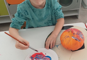 dziecko ozdabia dynię