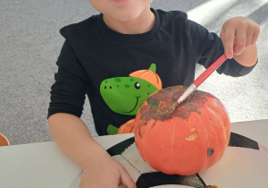 dziecko ozdabia dynię