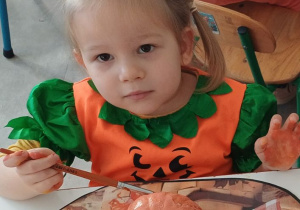 dziecko ozdabia dynię