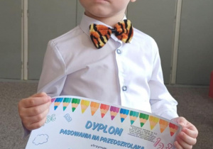 dziecko trzyma dyplom z okazji pasowania