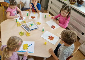 Dzieci podczas tworzenia ludzików z jesiennych liści