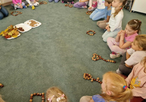 Dzieci z ułożonymi z kasztanów i orzechów wybranymi przez siebie kształtami