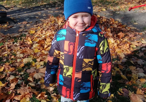 Chłopiec pozuje do zdjęcia w jesiennym ogrodzie przedszkolnym