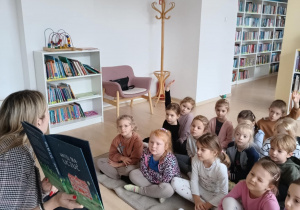 Dzieci oglądają ilustrację w książce czytanej przez Panią bibliotekarkę