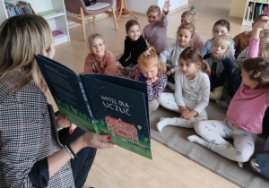 Dzieci słuchają książki czytanej przez Panią bibliotekarkę