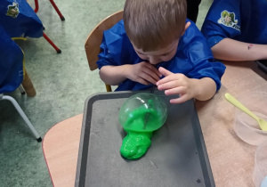 Chłopiec nadmuchuje balon z własnoręcznie stworzonej masy sensorycznej