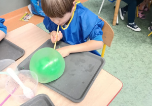 Chłopiec nadmuchuje balon z własnoręcznie stworzonej masy sensorycznej