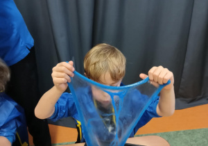 Chłopiec tworzy rozciągliwe lusterko z własnoręcznie uformowanej masy sensorycznej