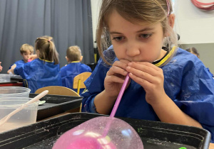 Dziewczynka nadmuchuje balon z własnoręcznie stworzonej masy sensorycznej