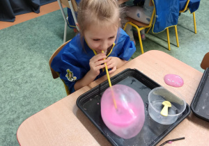 Dziewczynka nadmuchuje balon z własnoręcznie stworzonej masy sensorycznej