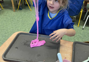 Dziewczynka robi spadający wodospad z własnoręcznie uformowanej masy sensorycznej