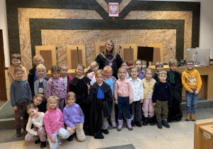 Dzieci pozują do zdjęcia z Panią Sędzią na tle stołu sędziowskiego