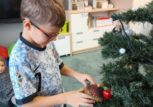 Chłopiec zawiesza ozdoby na choince