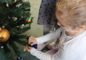 Dziewczynka zawiesza ozdoby na choince